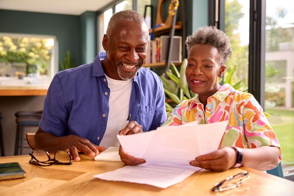 smiling senior couple sitting around table and looking over sheets of paper